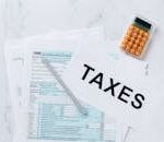 Top view of tax forms, a calculator, and pen for tax preparation.